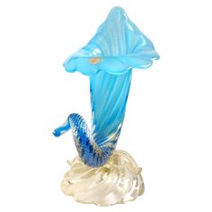 a blue glass figurine sitting on top of a white base with a flower