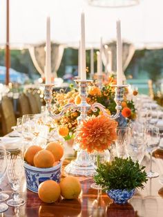 the table is set with oranges and wine glasses, candlesticks, and flowers