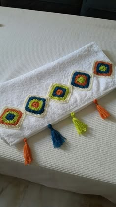 a white towel with tassels on it sitting on top of a bed next to a pillow