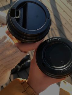 two people holding up coffee cups with lids