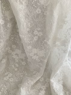 an image of white lace fabric with flowers on the bottom and sides, close up