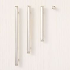 three metal handles on a wooden surface with one door handle and the other two knobs