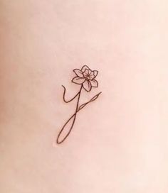 a single flower tattoo on the back of a woman's stomach, with a thin line