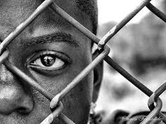 a man is looking through the bars of a fence with his eyes wide open and one eye partially closed