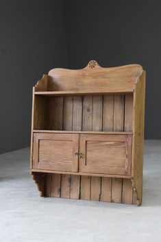 an old wooden bookcase with drawers and cupboards on the bottom, in front of a gray wall