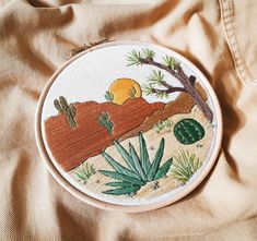 an embroidered desert scene with cacti and succulents