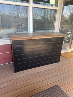 a large black chest sitting on top of a wooden floor next to a window in front of a building