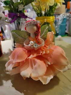 a small doll sitting on top of a table next to flowers