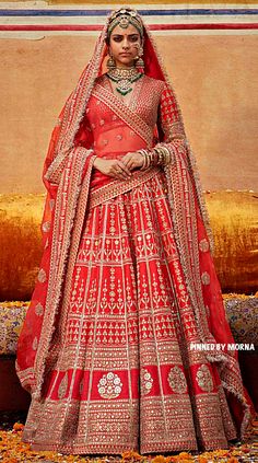 a woman in a red and gold bridal gown standing next to an orange couch