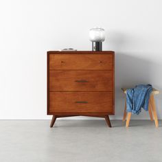 a wooden dresser sitting next to a white wall with a lamp on top of it