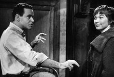 an old black and white photo of a man talking to a woman in a chair