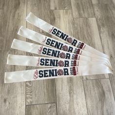 four white ribbons with the words senior, senior and senior printed on them sitting on a wood floor