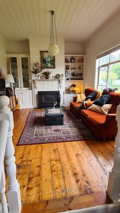 a living room filled with furniture and a fire place next to a window on top of a hard wood floor