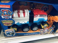 a toy truck in the shape of a dinosaur with other toys on display for sale