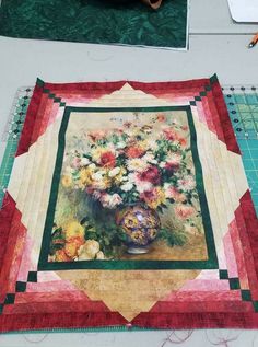 a quilted table runner with flowers in a vase on it next to a pair of scissors