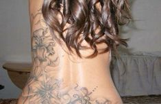 the back of a woman's body with tattoos on it