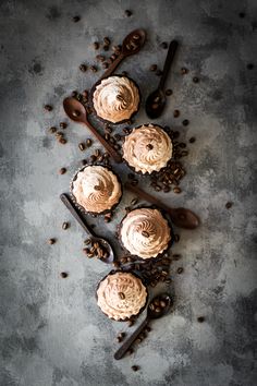 three chocolate cupcakes with white frosting and coffee beans on a gray background