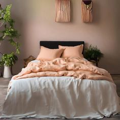 a bed with two plants on the wall above it