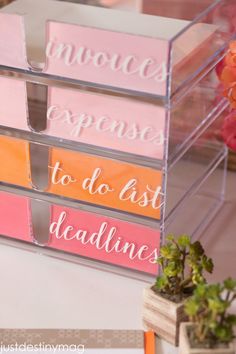 three clear acrylic boxes with pink and orange dividers on the sides, each containing words