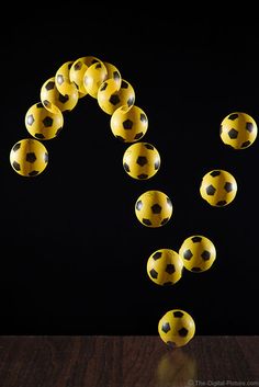 a group of yellow and black balls floating in the air on top of a wooden table