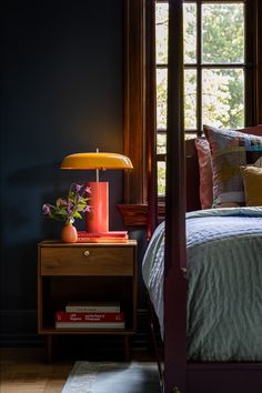 a bed room with a neatly made bed and a night stand next to a window