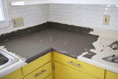 a kitchen with yellow cabinets and white counter tops that has been torn off from the wall