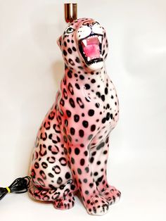 a pink and black cheetah sitting on top of a white surface with its mouth open