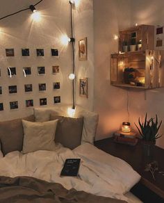 an unmade bed with pillows and lights on the wall