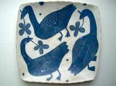 a blue and white plate with two birds on it's side, in the shape of a square