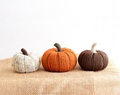 three knitted pumpkins sitting on top of a burlock covered tablecloth