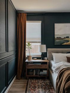 a bedroom with black walls and white bedding has a painting on the wall next to it