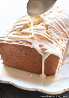 a spoon drizzling icing onto a loaf of bread on a plate