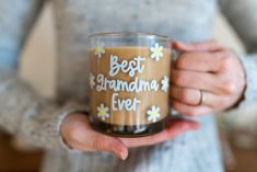 a woman holding a coffee mug with the words best grandma ever written on it