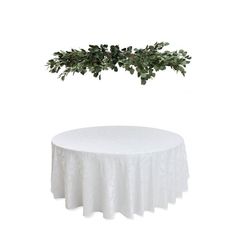 a table with a white cloth and green leaves on it, against a white background