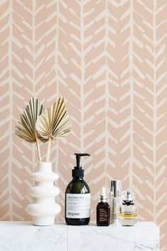 an assortment of skin care products on a marble countertop in front of a wallpaper