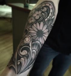 a woman's arm with flowers and swirls on the back of her arm