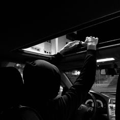 two people are driving in the dark with their hands on the steering wheel and one person is reaching for something