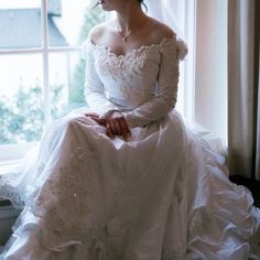 a woman in a wedding dress sitting on a window sill