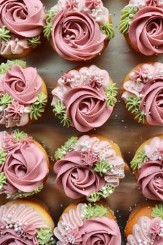 many cupcakes with pink frosting and flowers on them are arranged in rows