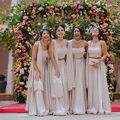 the bridesmaids are posing for a photo in front of an arch with flowers