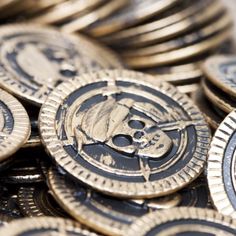 a pile of gold and black coins with skulls in the middle on top of them