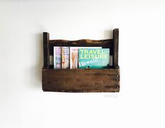 a wooden shelf with books and magazines in it on the wall next to a white wall