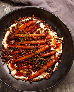 carrots and chickpeas with yogurt sauce in a black bowl on a table