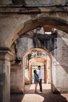 a man and woman standing in an archway between two buildings