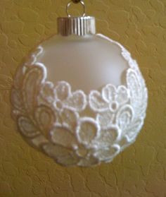 a white glass ornament hanging from a hook on a wall with a gold background