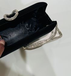 The Black Clutch Purse is a stylish blend of sophistication and glamour. It is crafted with precision and attention to details. This satin evening clutch is a must have addition to your accessory collection. It will glamorize your look and is spacious enough to carry all the essentials. The clutch comes with a detachable chain strap so you can carry it as a clutch or a shoulder bag. Dimensions: (LxW): 7.67 inches x 4.33 inches Material: Satin exterior and interior, Rhinestones Features: Kiss Loc Chic Crystal-embellished Evening Bag For Cocktails, Chic Black Evening Bag With Rhinestones, Trendy Clutch Evening Bag For Night Out, Chic Black Clutch For Formal Occasions, Chic Black Formal Clutch, Black Evening Bag With Rhinestones, Black Rhinestone Clutch For Party, Black Rhinestone Evening Bag, Luxury Silver Clutch For Evening