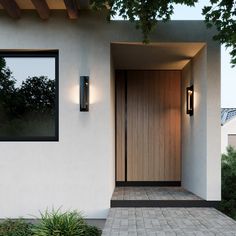 an entrance to a house with two lights on the side and brick walkway leading up to it