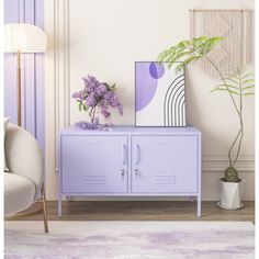 a purple cabinet sitting next to a white chair in a living room with a plant on top of it