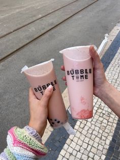 two people holding up pink cups with bubble time on the top and one has a straw in it