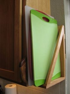 a green cutting board sitting on top of a wooden cabinet